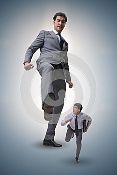 The bad angry boss kicking employee in business concept