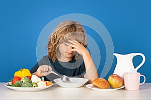 Bad appetite. Sad kid eating healthy food on studio iosolated background. Baby eat soup with spoon. Kid eating soup.