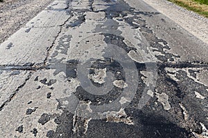 a bad asphalt road that has been repaired many times