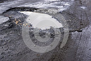 Bad asphalt road with pit and puddle