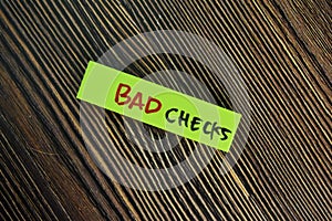 Bad Checks write on sticky notes isolated on Wooden Table