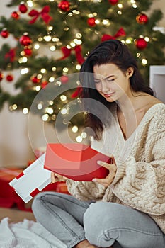 Bad Christmas Gift - Disappointed and Unhappy Woman with Opened Present Box Indoors at Home