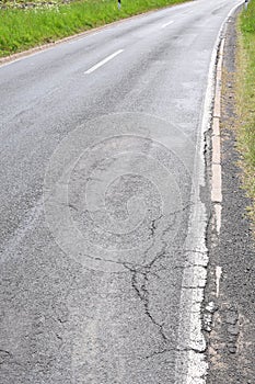 a bad country road with cracks and crumbling sides photo