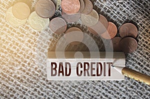 Bad credit text on wooden block and coins on burlap canvas. Crisis times unpaid loand and credits financial business concept
