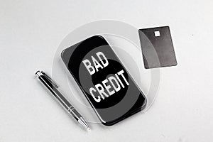 BAD CREDIT word on smartphone with credit card and pen