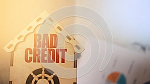 Bad Credit words on wooden home model with financial diagram background. Debts , house loan, real estate concept