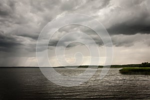 Bad dark weather with clouds and rain on a lake