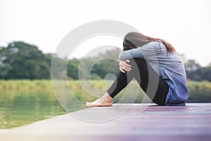Bad Day Concept. Sadness Woman Sitting by the River on Wooden Patio Deck
