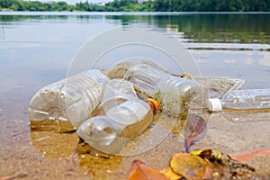 Bad environmental habit of improper disposal of non-biodegradable PVC cups and bottles in a lake. Selective focus.