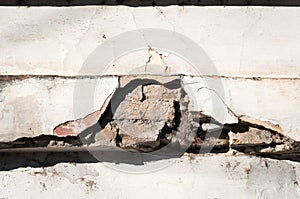 Bad foundation base on old house or building cracked plaster facade wall with brick background