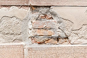 Bad foundations on old house cracked plaster wall with brick background