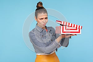 Bad gift. Upset frustrated woman unpacking present, opening small carton box and looking at camera with funny displeased