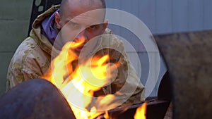 Bad guy looking on camera through the bonfire.