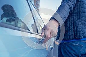 Bad guy scratching the car door with a screwdriver in the parking lot on the street. Damage of property from revenge for treason