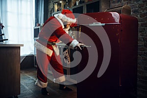 Bad impudent Santa claus opens the refrigerator