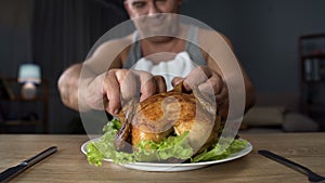 Bad-mannered overweight man tearing piece of chicken with hands, overeating