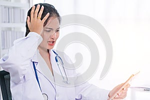 Bad medical results female doctor looking at computer tablet and looking confused in lab coat hospital