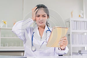 Bad medical results female doctor looking at computer tablet and looking confused in lab coat hospital