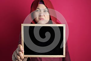 Bad mood angry annoyed Asian muslim woman shows empty blackboard