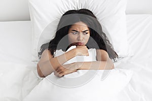 Bad morning sleep concept. Upset african american woman waking up and lying in bed, feeling angry