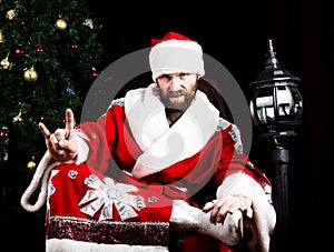 Bad rastoman Santa Claus doing different finger signs on the background of Christmas tree