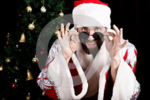 Bad rastoman Santa Claus holds round glasses and smiles, on the background of Christmas tree. different funy emotions