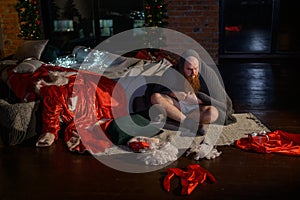 Bad Santa Claus on the background of Christmas decorations. A man in a suit of Santa Claus after the New Year`s
