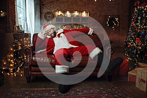 Bad Santa claus with hangover sitting on couch