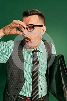 Bad smell. Portrait of handsome man, businessman in classical suit covering nose with hand over green studio background