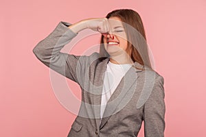 Bad smell! Portrait of young woman in business suit pinching nose and frowning in displeasure, expressing repulsion