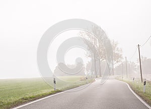 Bad visibility in autumn on a foggy country road