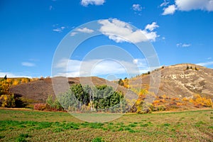 Badland hills with dry grass and trees and blue sky