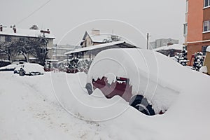 Badly cleaned roads after snow storm. Cars covered with snow in city. Automobiles stuck in heaps after winter blizzard