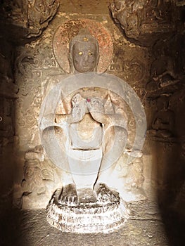 Badly damaged image of a seated Buddha in teaching pose Dharmacakra mudra in inner sanctum of Aurangabad Cave 2, India