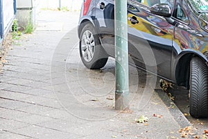 Badly parked car with tire on pavement shows wheel on walkway as traffic violation with penalty for poor driving and parking viola