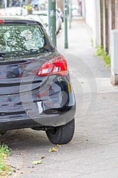 Badly parked car with tire on pavement shows wheel on walkway as traffic violation with penalty for poor driving and parking viola