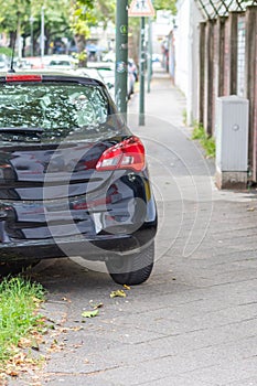 Badly parked car with tire on pavement shows wheel on walkway as traffic violation with penalty for poor driving and parking viola