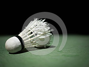 Badminton ball or shuttlecock located on the green ground with a black background.that have been hit or practiced to the extreme.