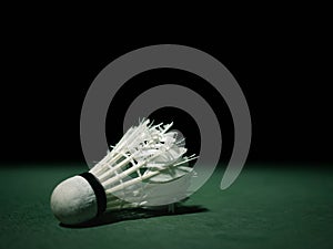 Badminton ball or shuttlecock located on the green ground with a black background.that have been hit or practiced to the extreme.