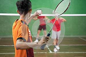 badminton player in orange uniform ready to serve