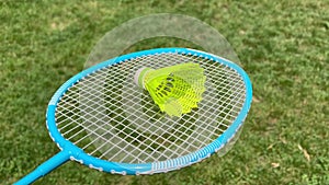 Badminton racket holding white used shuttlecock against grass background