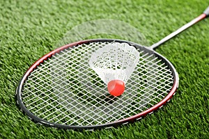 Badminton racket and shuttlecock on green grass outdoors, closeup