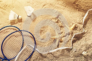 Badminton rackets, net, shuttlecock and starfish on the sand
