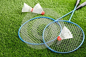 Badminton rackets and shuttlecocks on green grass outdoors
