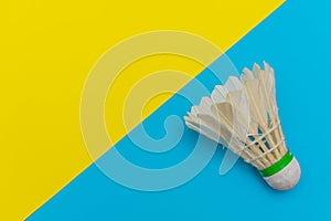 Badminton shuttlecock or birdie on a solid bright blue and yellow flat lay background symbolizing sports and activity with copy