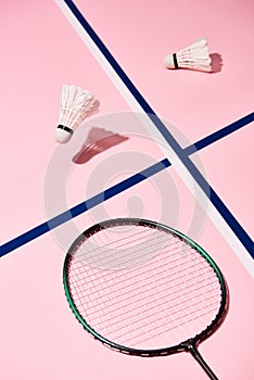 Badminton shuttlecocks and racket on pink background