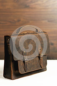 Bag briefcase for businessman men, leather brown bag on a wooden background. Men`s fashion, accessory, business background.