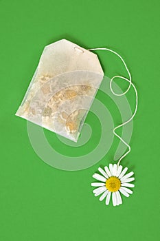 Bag of chamomile tea over green background