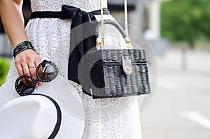 Bag closeup in female hands. Black and white image style. Women`s accessories: watches, glasses, rings and bracelets.