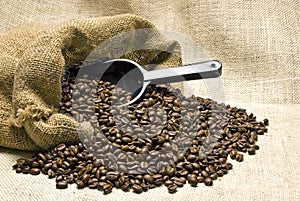 Bag Of Coffee Beans With Scoop And Burlap Background
